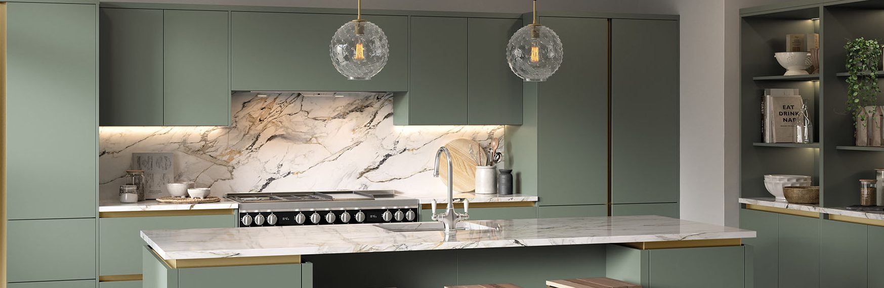 Handleless kitchen with rich green cabinetry, gold hardware and marble countertops, blending bold colour with luxe finishes.